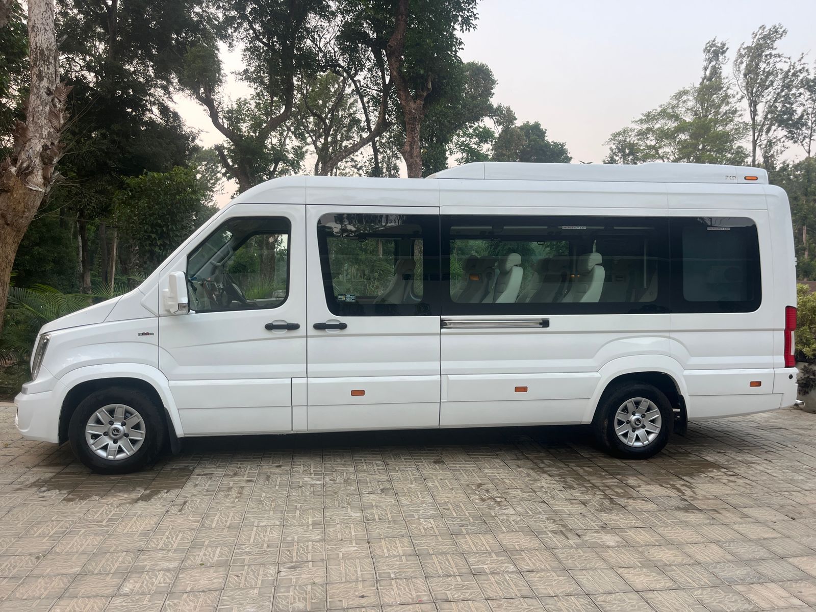 Tempo Traveller side profile parked under trees
