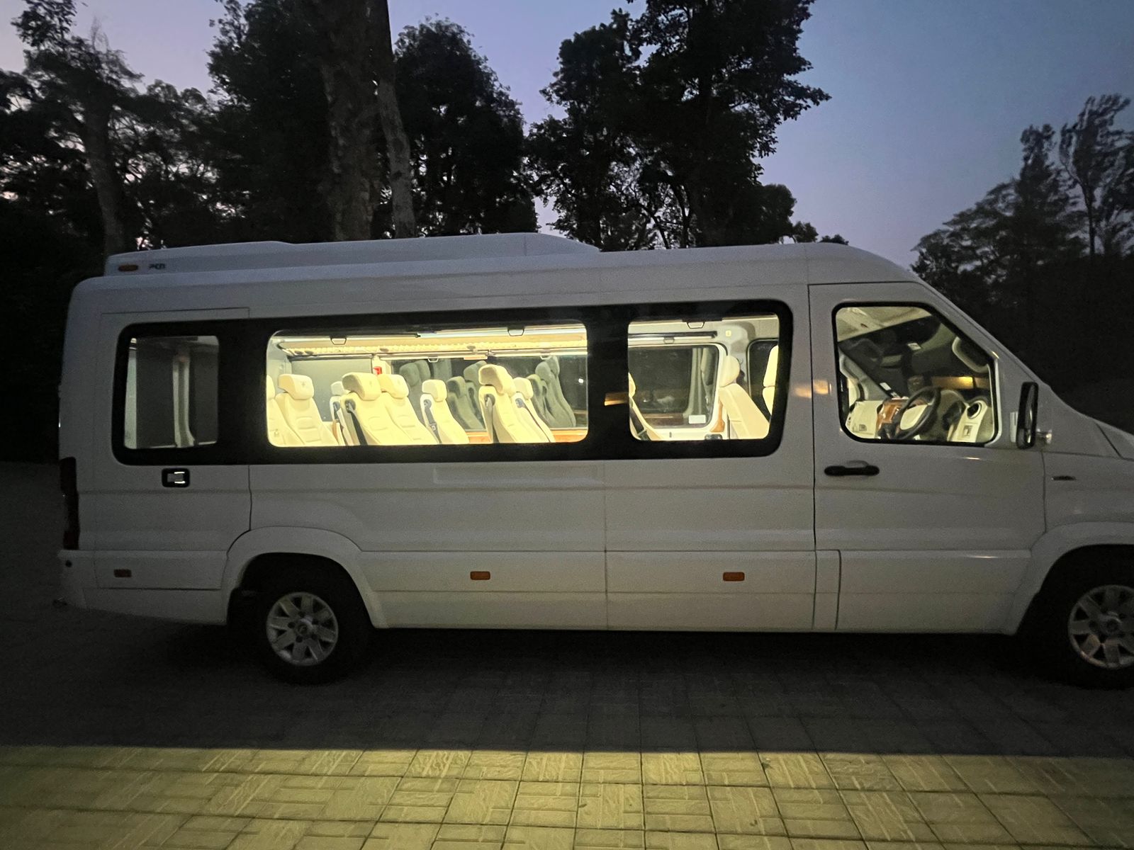 Tempo Traveller lit up at dusk with plush interiors